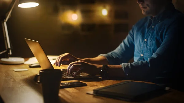 Anonieme man zit aan zijn bureau in Office Studio werken aan een laptop in de avond. Man werkt met data, Statistieken analyseren. — Stockfoto