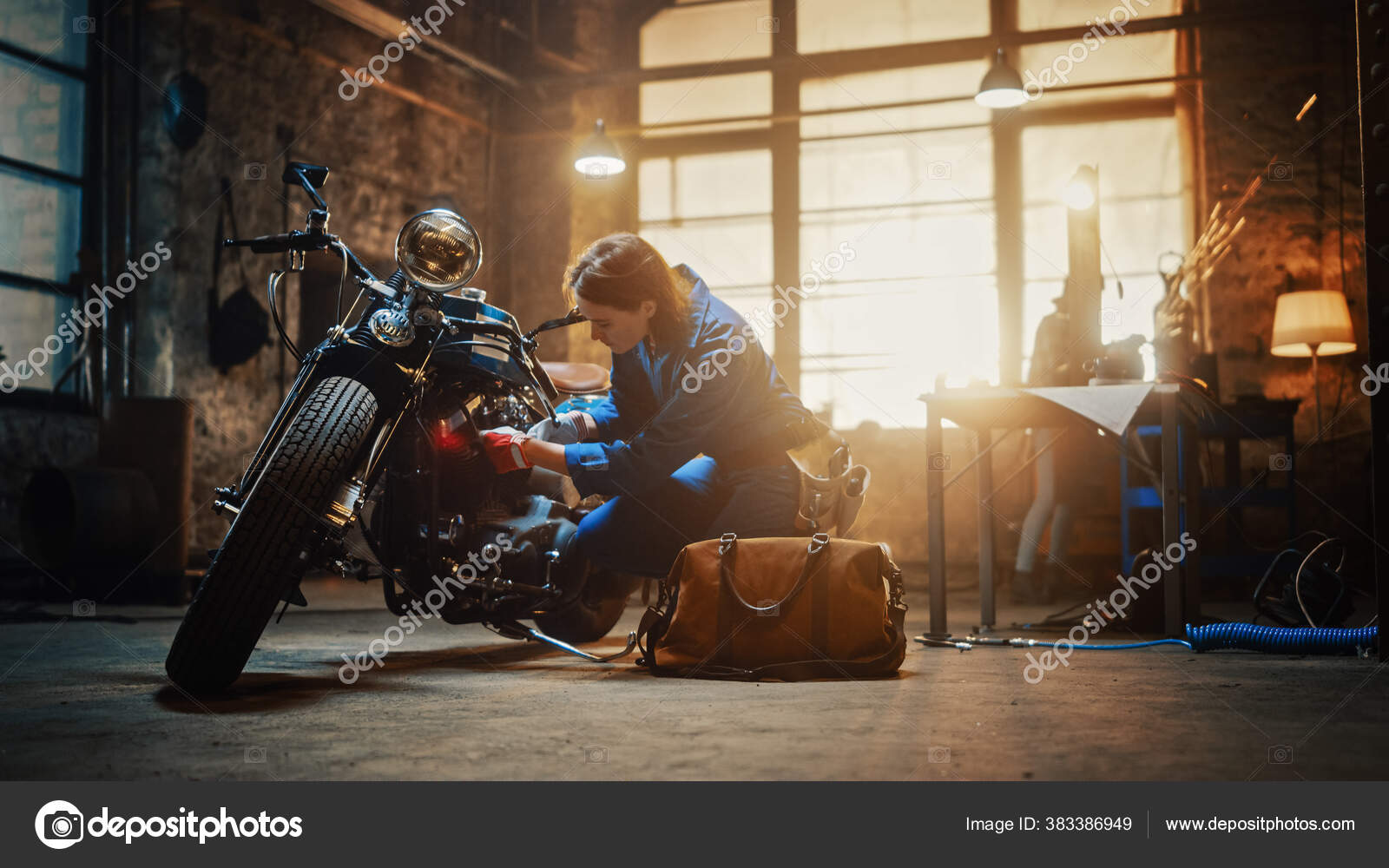 Young Beautiful Female Mechanic is Working on a Custom Bobber Motorcycle.  Talented Girl Wearing a Blue