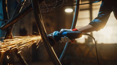 Metal Üreticisinin Elleri Kapalı Güvenlik Eldiveni Giyen ve Stüdyoda Açılı Öğütücüyle Çelik Tüpü Heykeli Yapan. Bir atölyede el bilgisayarı ile çalışmak.
