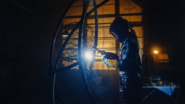 Genç Çağdaş Kadın Sanatçı, Metal Tüpü Heykelini Bir Stüdyo Atölyesinde El Altındaki Güç Aracı ile Kaynak Yapıyor. Güçlendirici Kadın Metalden Modern Vahşi Sanatsal Çalışmalar Yapıyor.