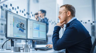 Bir Kişisel Bilgisayar üzerinde çalışan Endüstriyel Mühendis, İki Monitör, Melez Elektrik Motoru ve Haritaları 'nın 3 boyutlu prototipiyle CAD yazılımını gösteriyor. Çalışan Modern Fabrika.