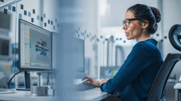 Ingeniera Industrial Trabajando en una computadora personal, dos pantallas de monitor muestran software CAD con prototipo 3D de nuevo motor de hidrógeno híbrido y gráficos. Fábrica moderna con maquinaria de alta tecnología —  Fotos de Stock