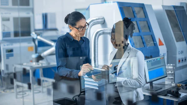 Ingeniero industrial habla con el supervisor del proyecto, utilizan la computadora digital de la tableta y discuten la planificación moderna de la fábrica. Instalación de fabricación con maquinaria CNC y línea de montaje de brazo de robot — Foto de Stock