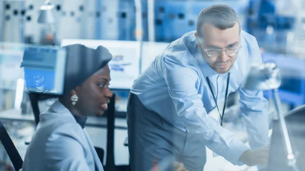 현 재의 Factory: Male Project Supervisor Talks to a Female Industrial Engineer who works on Personal Computer. 샷 Through Glass in Modern High-Tech Industrial Factory Office. — 스톡 사진