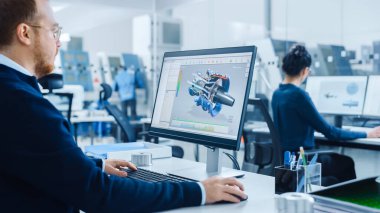 Omuz üstü: Ağır Sanayi Mühendisi Kişisel Bilgisayar 'da çalışıyor, Ekranda Yeni Nesil Elektrik Motoru Gösteren CAD Yazılımı görülüyor. Yüksek teknoloji CNC Makineli Endüstriyel Fabrika
