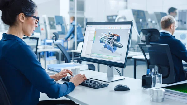 Ingeniera industrial femenina Trabajando en una computadora personal, Screen muestra el software CAD con el prototipo 3D del motor. Fábrica ocupada con trabajadores profesionales Maquinaria de alta tecnología —  Fotos de Stock