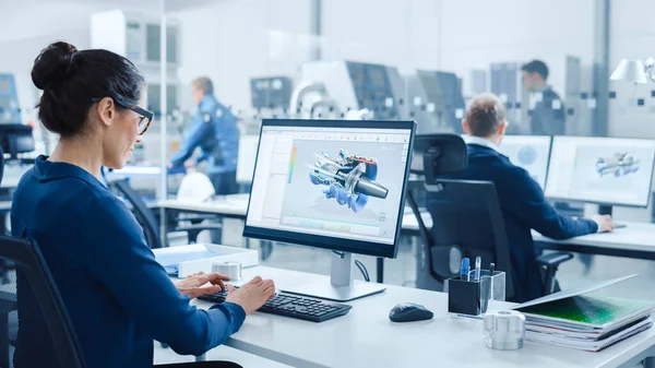 Industrial female Engineer Working on a Personal Computer, Screen shows CAD Software with 3D Prototype of Electric Engine. V pozadí moderní továrna s high-tech CNC strojírenství — Stock fotografie
