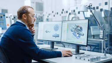 Erkek Endüstriyel Mühendislik Çözme Sorunları, Kişisel Bilgisayar üzerinde çalışırken, İki Monitör, Hibrit Elektrik Motoru Testi 'nin 3 boyutlu prototipiyle CAD Yazılımını gösteriyor. Çalışan Modern Fabrika