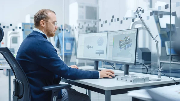 Ingeniero industrial masculino Resolviendo problemas, trabajando en una computadora personal, dos pantallas de monitor muestran software CAD con prototipo 3D de motor eléctrico híbrido que se está probando. Fábrica moderna de trabajo —  Fotos de Stock