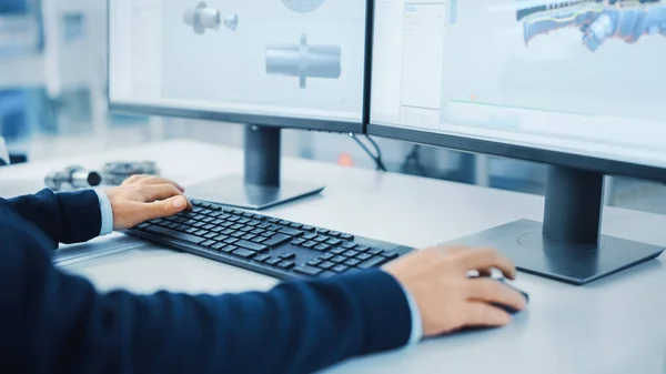 在个人计算机上工作的工业工程师的特写镜头，使用鼠标和键盘，两个监视器屏幕在3D中用机床显示CAD软件. — 图库照片