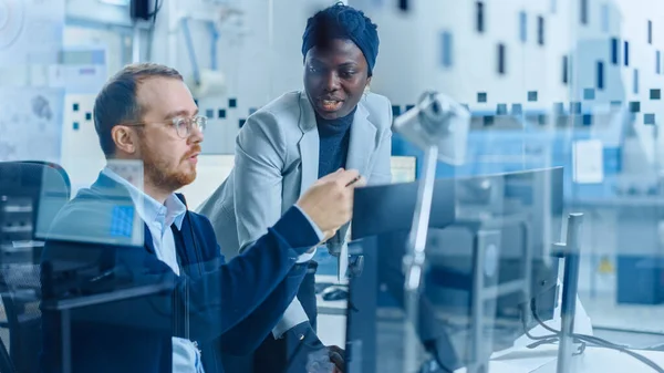 Modern Electronic Factory: Female Project Manager Talks to Male Electrical Engineer who Works on Computer with CAD Software. Developing PCB, Microchips, Semiconductors and Telecommunications Equipment — Stock Photo, Image