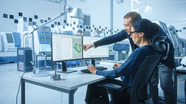 Modern Electronics Factory: Male Supervisor Talks to a Female Electrical Engineer, який працює над комп'ютером з CAD Software. Розробка ПКБ, мікрочипів, напівпровідників і телекомунікаційного обладнання — стокове фото