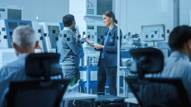 Modern Factory: Yüksek Teknoloji Geliştirme Tesisi 'nde duran, konuşan ve tablet bilgisayar kullanan kadın proje yöneticisi erkek mühendisi. CNC Makineli Çağdaş Tesis, Robot Arm Üretim Hattı