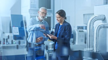 Modern Fabrika: Kadın Mühendis, Erkek Proje Yöneticisi Yüksek Teknoloji Geliştirme Tesisi, Konuşma ve Tablet Bilgisayar Kullanımı. CNC Makineli Çağdaş Tesis, Robot Arm Üretim Hattı