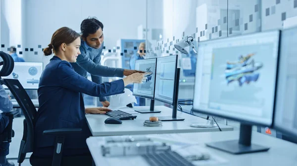 Inside Factory Office: Male Project Supervisor Talks to a Female Industrial Engineer who Works on Computer, Talk. In Workshop: Professional Workers Use High-Tech Industry 4 CNC Machinery, Robot Arm. — Stock Photo, Image