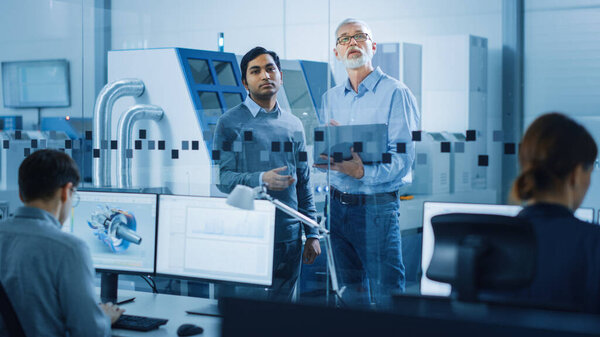 Automotive Design Factory: Project Manager, Chief Mechanical Engineer Talk, Use Laptop, Discuss Project Details. High-Tech Industrial Facility Construction of Engines using CNC Machinery.