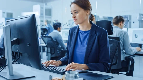 Escritório de fábrica moderna: Retrato de Jovem e Confiante Engenheira Industrial Feminina Trabalhando em Computador. Fábrica industrial com engenheiros de design da indústria trabalhando em computadores, oficina de máquinas CNC — Fotografia de Stock