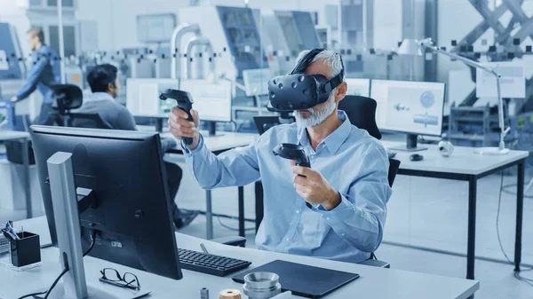 Industrial Design Engineer Dragen Virtual Reality Headset en Holding Controllers, maakt gebruik van VR-technologie voor Industrial Design, Ontwikkeling met behulp van Computer. Modern fabriekskantoor, Werkplaats met machines — Stockfoto