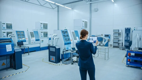 Fábrica moderna: La ingeniera femenina utiliza la computadora digital de la tableta con el software de la realidad aumentada para visualizar el taller para el mapeo de la habitación, disposición del piso. Instalación con maquinaria CNC de alta tecnología y brazo de robot — Foto de Stock