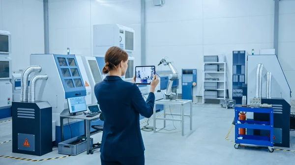 Fábrica moderna: La ingeniera femenina utiliza la computadora digital de la tableta con el software de la realidad aumentada para visualizar el taller para el mapeo de la habitación, disposición del piso. Instalación con maquinaria CNC de alta tecnología y brazo de robot — Foto de Stock