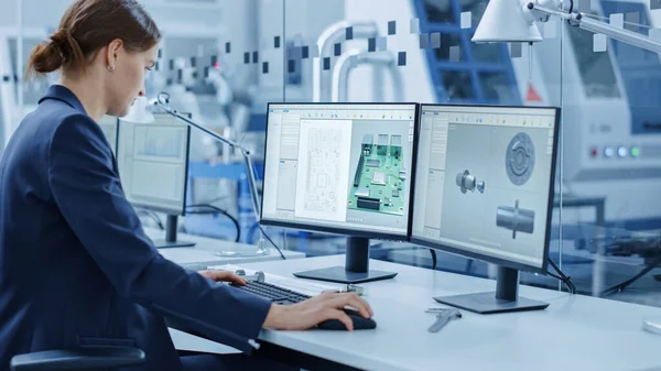 Женщина-инженер, работающая на персональном компьютере, два монитора показывают хрому ключевого зеленого экрана дисплея и программное обеспечение САПР с 3D-моделью промышленного машиностроения. Работа на современной фабрике — стоковое фото