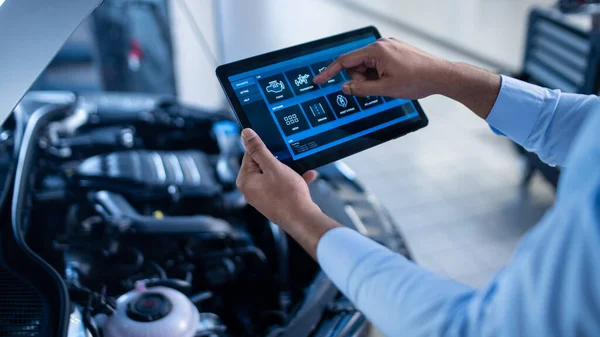 Car Service Manager or Mechanic Utiliza una Tablet Computer con un software de diagnóstico interactivo futurista. Especialista que inspecciona el vehículo para encontrar componentes rotos en la bahía del motor . — Foto de Stock