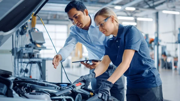 Belo Empoderamento Feminino Mecânico está trabalhando em um carro em um serviço de carro. Mulher em óculos de segurança está consertando o motor. Usa um catraca. Oficina limpa moderna com carros . — Fotografia de Stock