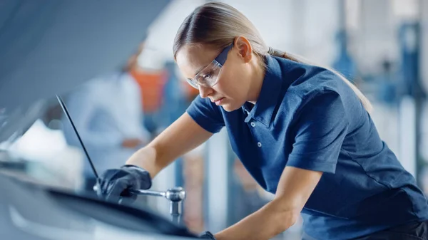 Porträtt Skott av en kvinnlig mekaniker som arbetar på ett fordon i en bilservice. Stärker kvinnan Fixar motorn. Hon använder en Ratchet. Modern Clean Workshop. — Stockfoto