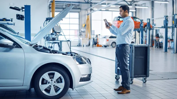 Car Service Manager utilise un ordinateur tablette avec un logiciel de diagnostic de réalité augmentée. Spécialiste Inspection de la voiture afin de trouver des composants cassés à l'intérieur du compartiment moteur. — Photo