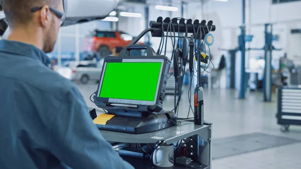 Autó szerviz szerelő fut egy diagnosztikai szoftver egy fejlett számítógép zöld képernyő. Szakember ellenőrzése a jármű annak érdekében, hogy megtalálja a törött alkatrészek és hibák az adatnaplók. — Stock Fotó