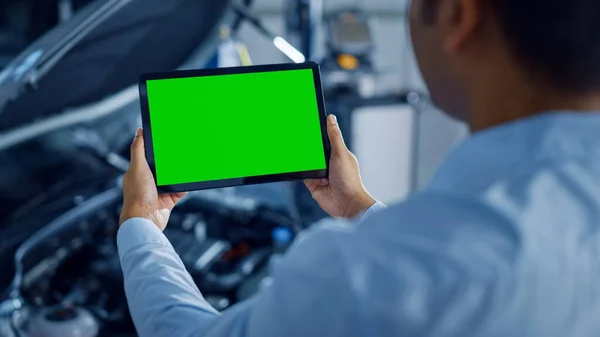 Car Service Manager eller mekaniker Använder en surfplatta Dator med en grön skärm Mock Up som är pekade på en Enginer Bay. Specialist Inspektera fordonet för att hitta trasiga komponenter i motorn — Stockfoto