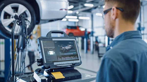 Car Service Manager or Mechanic is Running an Interactive Diagnostics Software on an Advanced Computer. Specialist Inspecting the Vehicle in Order to Find Broken Components and Errors in Data Logs. — Stock Photo, Image