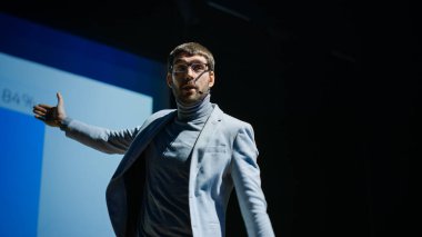 İlham verici Erkek Konuşmacı Yeni Teknolojik Ürünleri Sunuyor, Büyük Ekranda Bilgi, İstatistik Animasyonu, Aygıt Performansı Hakkında Konuşuyor. Canlı Olay Başlatma Konferansı