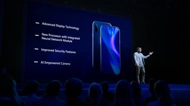 Gıcır gıcır ürünlerle canlı etkinlik Reveal: Keynote Sözcüsü Smartphone Cihazını Seyirciye Sunar. Sinema Sineması Ekranında Yüksek Teknolojik Özellikleri ve Üst Işıkları Olan Dokunmatik Ekran Telefonu Gösterildi