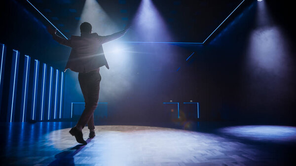 Знаменитый артист выходит на сцену, приветствует зрителей, начинает представление. Основатель компании-разработчика программного обеспечения, Гуру технологического маркетинга, выступающий с докладом. Кинематографический вид сзади
