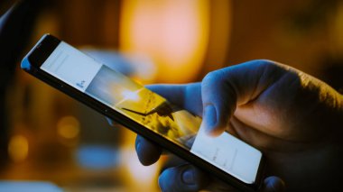 Yakın plan Macro: İnsan Tutma ve Akıllı Telefon Kullanma, Sosyal Ağ Duvarındaki Resimlere Bakma. Parmak Kaydırma Sosyal Medya Uygulaması: Seyahat, Hayvanlar, Yiyecek. Model Uygulama Tasarımı