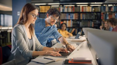Üniversite Kütüphanesi: Yetenekli Kafkasyalı Kız Laptop, Akıllı Sınıf Arkadaşı Açıklamaları ve Sınıf Ödeviyle Ona Tavsiye Veriyor. Mutlu Çeşitli Öğrenciler Konuşuyor, Öğreniyor, Sınavlar İçin Birlikte Çalışıyor
