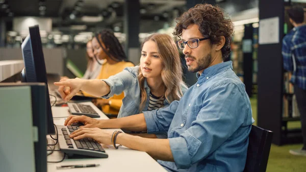 Biblioteca Universitária: Garota Caucasiana Brilhante e Garoto Inteligente Juntos Trabalhar em Computadores, bate-papo, discutir atribuição de classe, explicar e aconselhar uns aos outros. Grupo Diverso de Estudantes Exame Trabalho em Equipe — Fotografia de Stock