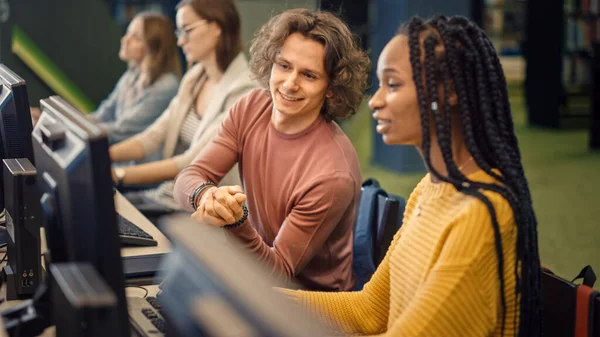 Rij van Computer in de Universiteitsbibliotheek: Gericht Bright Caucasian Boy en getalenteerde Black Girl Studie voor Examens, Werk aan Opdracht, Punt op het scherm, Praten, Op zoek naar oplossing, Leg uit Onderwerp — Stockfoto