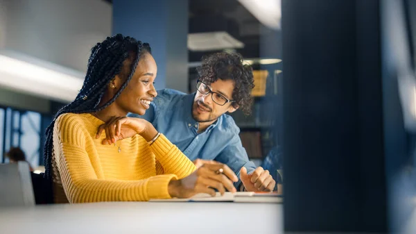 Universitetsbiblioteket: Gifted Black Girl använder laptop, Smart Classmate Förklarar och hjälper henne med klass uppdrag. Glad mångfald studenter talar, lär, studerar tillsammans för tentor — Stockfoto