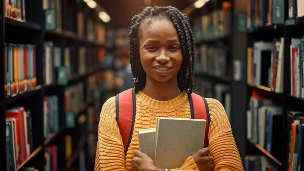 University Library Study: Portrait of a Smart Beautiful Black Girl Holding Study Text Books Smiling Looking at the Camera (en inglés). Estudiante auténtico investiga para asignación de clases, preparación de exámenes —  Fotos de Stock