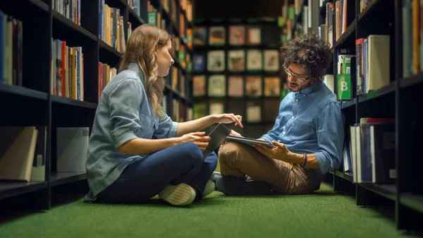 Estudio de la Biblioteca Universitaria: Muchacha blanca inteligente sentada y talentoso niño hispano sentado con las piernas cruzadas en el suelo, hablar, usar computadoras portátiles, colaborar y discutir el papel, estudiar y prepararse para los exámenes —  Fotos de Stock