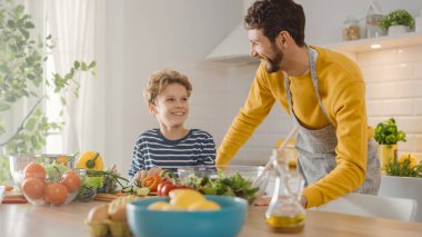 Baba ve Şirin Oğul Sağlıklı Yemek Yapıyor. Babam Küçük Çocuk 'a sağlıklı alışkanlıklar ve salata için sebze kesmeyi öğretiyor. Mutlu Çocuk ve Ebeveynler Birlikte Zaman Geçirir