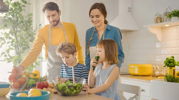 In Kitchen: Family of Four Cooking Together Healthy Dinner. Mother, Father, Little Boy and Girl, Preparing Salads, Washing and Cutting Vegetables. Cute Children Helping their Beautiful Caring Parents — Stock Photo, Image