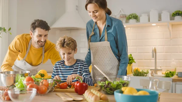 In Kitchen: Family of Three Cooking Together Healthy Dinner. Mother and Fathe Teach Little Boy Healthy Habits and to Cut Vegetables for Dinner Salad. Cute Child Helping their Beautiful Caring Parents — Stock Photo, Image