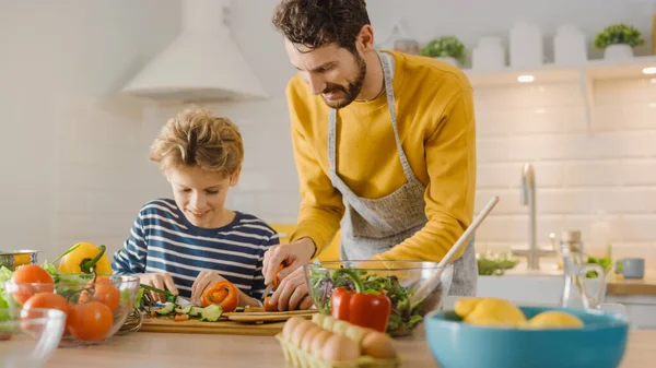 In the Kitchen: Father and Cute Little Son Cooking Together Healthy Dinner. Dad Teaches Little Boy Healthy Habits and how to Cut Vegetables for the Salad. Happy Child and Parent Spend Time Together — Stock Photo, Image