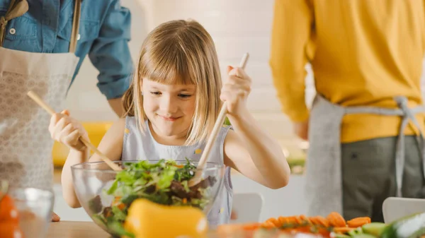 In Kitchen: Mother and Little Daughter Cooking Together Healthy Dinner. Mom Teaches Little Girl Healthy Habits and how to Mix Vegetables in Salad Bowl. Cute Child Helping Her Beautiful Caring Parents — Stock Photo, Image