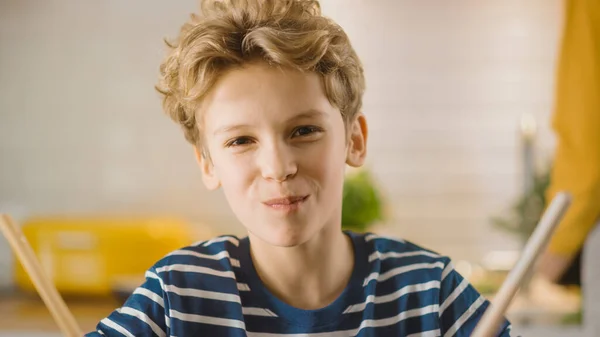 台所で:小さな男の子は食べ物のお菓子でいっぱいの口でカメラで笑っています。健康的なディナー。幼い息子は健康な習慣を学ぶ. — ストック写真