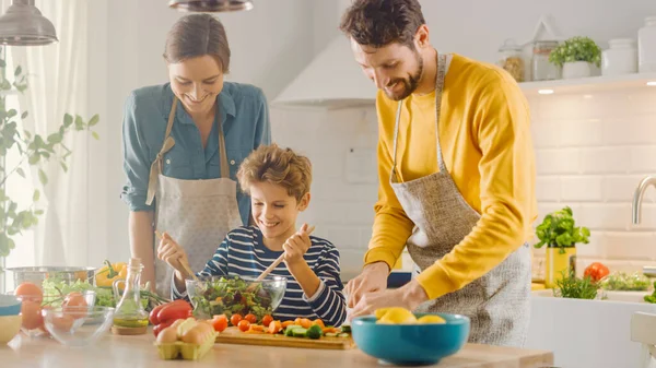 In Kitchen: Family of Three Cooking Together Healthy Dinner. Dad and Mom Teach Little Son Healthy Habits and how to Mix Vegetables in Salad Bowl. Cute Child Helping His Beautiful Caring Parents — Stock Photo, Image