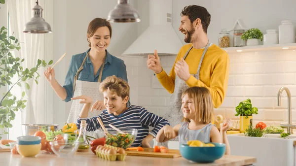 In Kitchen: Family of Four Cooking Together Healthy Dinner, Fool Around and Dance. Mother, Father, Little Boy and Girl, Preparing Salads, Cutting Vegetables. Cute Children Helping their Caring Parents — Stock Photo, Image